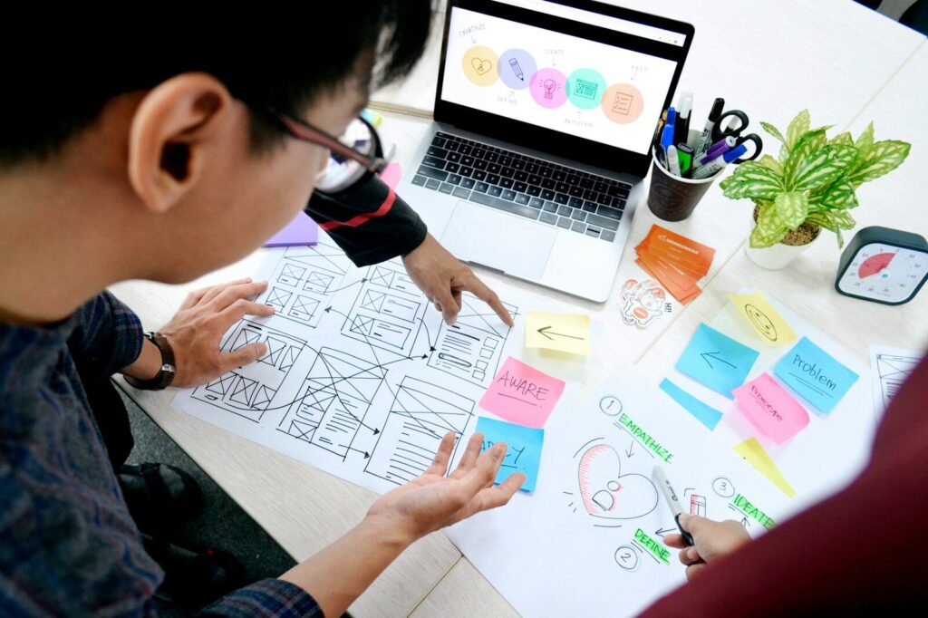 man designing wireframes at desk with laptop